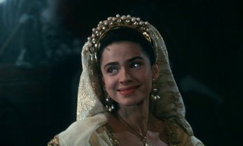 Movie still from “The Pit and the Pendulum” (1991), directed by Stuart Gordon – A woman wearing a headdress and a gold veil; Close Up shot, Over the shoulder angle