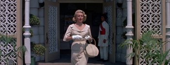 Movie still from “The Rains of Ranchipur” (1955), directed by Jean Negulesco – A woman in a white dress and white gloves; Medium shot, Low angle