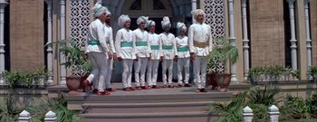 Movie still from “The Rains of Ranchipur” (1955), directed by Jean Negulesco – A group of men standing on steps wearing white and green uniforms; Wide shot, Low angle
