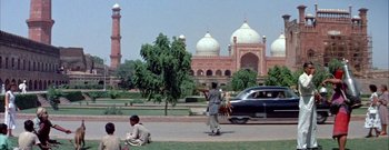 Movie still from “The Rains of Ranchipur” (1955), directed by Jean Negulesco – A man riding a skateboard down a sidewalk; Extreme Wide shot, High angle
