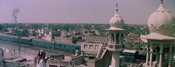 Movie still from “The Rains of Ranchipur” (1955), directed by Jean Negulesco – An aerial view of a city with a train on the tracks; Extreme Wide shot, High angle