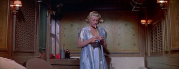 Movie still from “The Rains of Ranchipur” (1955), directed by Jean Negulesco – A woman smoking a cigarette while wearing a blue robe; Medium shot, Low angle