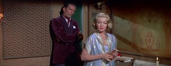 Movie still from “The Rains of Ranchipur” (1955), directed by Jean Negulesco – A man and a woman standing next to each other in a room; Medium shot, Low angle