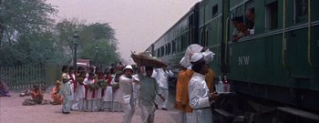 Movie still from “The Rains of Ranchipur” (1955), directed by Jean Negulesco – A group of people walking down a street near a train; Wide shot, High angle