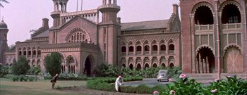 Movie still from “The Rains of Ranchipur” (1955), directed by Jean Negulesco – A man in a white shirt is in front of a building; Extreme Wide shot, Low angle