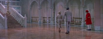 Movie still from “The Rains of Ranchipur” (1955), directed by Jean Negulesco – A man and a woman holding hands while walking in a room; Wide shot, High angle