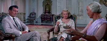 Movie still from “The Rains of Ranchipur” (1955), directed by Jean Negulesco – A woman sitting in a chair holding a bowl of tea; Medium shot, High angle