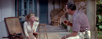 Movie still from “The Rains of Ranchipur” (1955), directed by Jean Negulesco – A man and a woman sitting on a porch; Medium shot, High angle