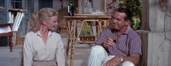 Movie still from “The Rains of Ranchipur” (1955), directed by Jean Negulesco – A man and a woman sitting on a porch; Medium shot, High angle