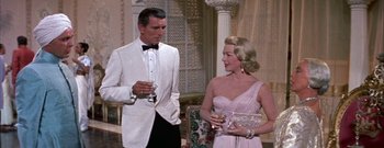 Movie still from “The Rains of Ranchipur” (1955), directed by Jean Negulesco – A man and a woman standing next to each other holding glasses; Medium shot, High angle