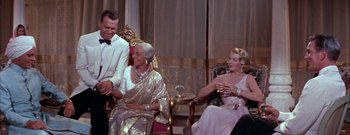 Movie still from “The Rains of Ranchipur” (1955), directed by Jean Negulesco – A group of people sitting around a room; Medium shot, Over the shoulder angle