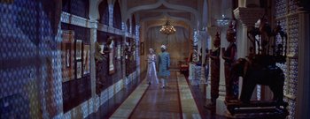 Movie still from “The Rains of Ranchipur” (1955), directed by Jean Negulesco – A couple of people that are walking down a hall way; Wide shot, High angle