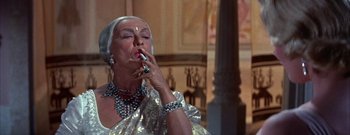 Movie still from “The Rains of Ranchipur” (1955), directed by Jean Negulesco – An older woman smoking a cigarette in a room; Close Up shot, High angle