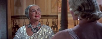 Movie still from “The Rains of Ranchipur” (1955), directed by Jean Negulesco – An older woman in a silver dress talking to a man in a black shirt; Close Up shot, Over the shoulder angle