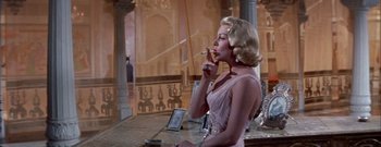 Movie still from “The Rains of Ranchipur” (1955), directed by Jean Negulesco – A woman smoking a cigarette while wearing a pink dress; Medium shot, Low angle