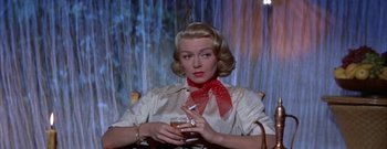 Movie still from “The Rains of Ranchipur” (1955), directed by Jean Negulesco – A woman sitting in a chair holding a glass of wine; Close Up shot, Low angle