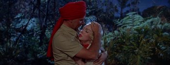 Movie still from “The Rains of Ranchipur” (1955), directed by Jean Negulesco – A man and a woman embracing each other in front of a forest; Medium shot, Low angle