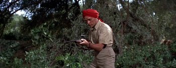 Movie still from “The Rains of Ranchipur” (1955), directed by Jean Negulesco – A man with a red turban holding a rifle; Medium shot, Low angle