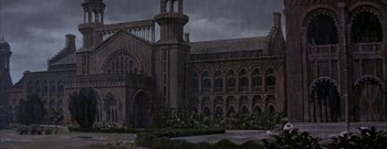 Movie still from “The Rains of Ranchipur” (1955), directed by Jean Negulesco – A large building with a clock tower in the middle of it; Extreme Wide shot, High angle