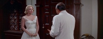 Movie still from “The Rains of Ranchipur” (1955), directed by Jean Negulesco – A woman in a white dress talking to an older man; Medium shot, Over the shoulder angle