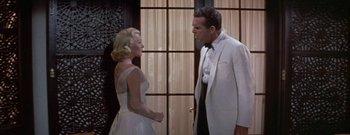 Movie still from “The Rains of Ranchipur” (1955), directed by Jean Negulesco – A man and a woman standing next to each other in front of a door; Medium shot, Low angle