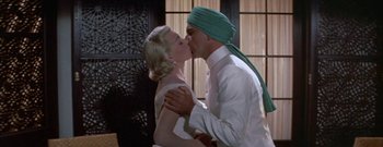 Movie still from “The Rains of Ranchipur” (1955), directed by Jean Negulesco – A man and a woman kissing each other in front of a door; Close Up shot, Low angle