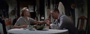 Movie still from “The Rains of Ranchipur” (1955), directed by Jean Negulesco – A man and a woman sitting at a table with a bowl of fruit on it; Medium shot, Over the shoulder angle