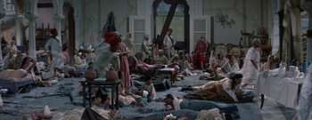 Movie still from “The Rains of Ranchipur” (1955), directed by Jean Negulesco – A group of people sitting and standing around a room; Wide shot, High angle