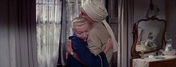 Movie still from “The Rains of Ranchipur” (1955), directed by Jean Negulesco – A man and a woman hugging each other in front of a window; Medium shot, High angle