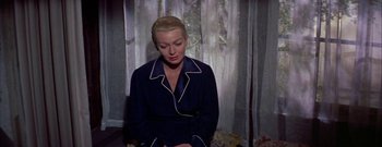 Movie still from “The Rains of Ranchipur” (1955), directed by Jean Negulesco – A woman sitting in front of a window in front of a curtain; Medium shot, High angle