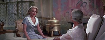 Movie still from “The Rains of Ranchipur” (1955), directed by Jean Negulesco – Two women sitting on the floor in front of an antique stove; Medium shot, Over the shoulder angle