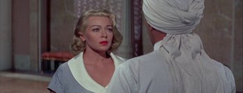 Movie still from “The Rains of Ranchipur” (1955), directed by Jean Negulesco – A woman with blonde hair and blue eyes looking at a man in a white turban; Close Up shot, Over the shoulder angle