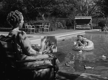 Movie still from “The Reluctant Dragon” (1941), directed by Jack Cutting – An older woman sitting in a chair next to a swimming pool; Wide shot, High angle