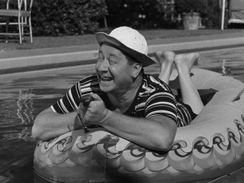 Movie still from “The Reluctant Dragon” (1941), directed by Jack Cutting – An older man in a hat is in a raft in the water; Medium shot, High angle
