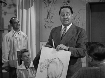 Movie still from “The Reluctant Dragon” (1941), directed by Jack Cutting – An old photo of a man holding an elephant drawing; Medium shot, Over the shoulder angle