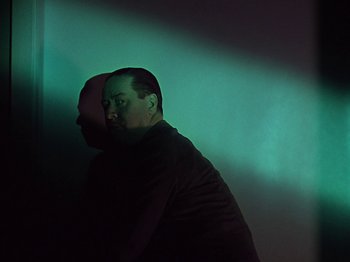 Movie still from “The Reluctant Dragon” (1941), directed by Jack Cutting – A man standing in a room with a green background; Medium shot, Low angle