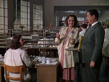 Movie still from “The Reluctant Dragon” (1941), directed by Jack Cutting – A group of people standing around a table; Medium shot, Over the shoulder angle