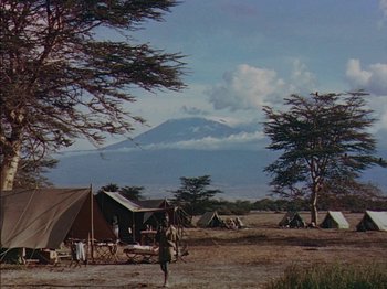 Movie still from “The Snows of Kilimanjaro” (1952), directed by Henry King – A group of tents in the middle of a field with a mountain in the background; Extreme Wide shot, Low angle
