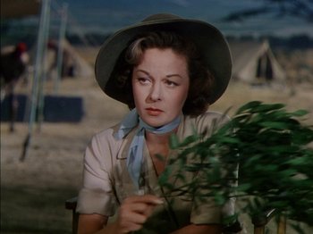 Movie still from “The Snows of Kilimanjaro” (1952), directed by Henry King – A woman sitting in front of a plant in front of a tent; Close Up shot, Low angle