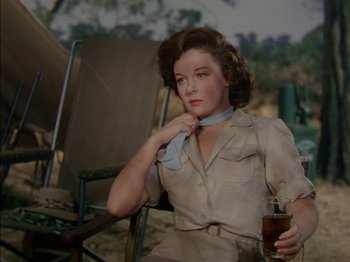 Movie still from “The Snows of Kilimanjaro” (1952), directed by Henry King – A woman sitting in a chair holding a glass of beer; Medium shot, Low angle