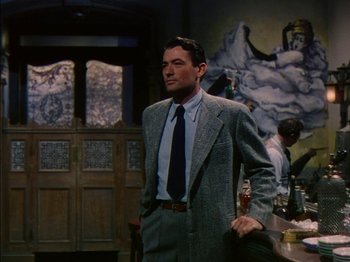 Movie still from “The Snows of Kilimanjaro” (1952), directed by Henry King – A man in a suit and tie standing in front of a bar; Medium shot, Low angle