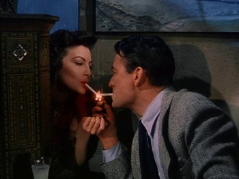 Movie still from “The Snows of Kilimanjaro” (1952), directed by Henry King – A man and a woman are lighting a cigarette; Medium shot, Overhead angle