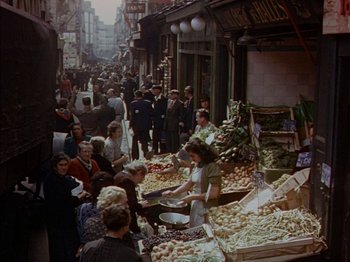 Movie still from “The Snows of Kilimanjaro” (1952), directed by Henry King – A group of people standing around a market with lots of vegetables; Extreme Wide shot, High angle