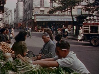 Movie still from “The Snows of Kilimanjaro” (1952), directed by Henry King – A group of people sitting on the side of the street; Wide shot, High angle