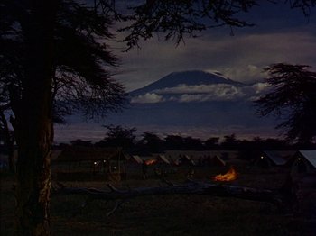 Movie still from “The Snows of Kilimanjaro” (1952), directed by Henry King – A group of tents in a field at night with a mountain in the background; Extreme Wide shot, Low angle