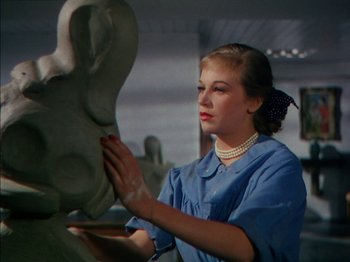 Movie still from “The Snows of Kilimanjaro” (1952), directed by Henry King – A woman in a blue shirt is working on a statue; Close Up shot, Low angle