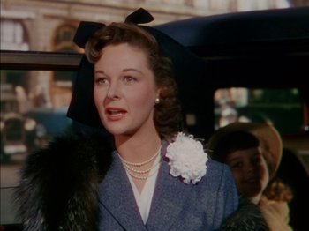 Movie still from “The Snows of Kilimanjaro” (1952), directed by Henry King – A woman with a flower in her hair holding an umbrella; Close Up shot, Low angle