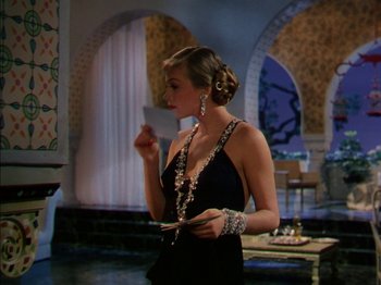 Movie still from “The Snows of Kilimanjaro” (1952), directed by Henry King – A beautiful woman in a black dress holding a card; Medium shot, Over the shoulder angle