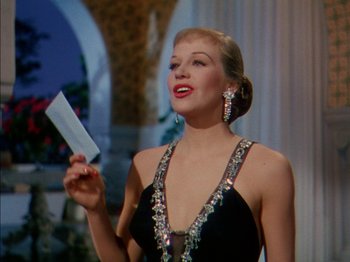 Movie still from “The Snows of Kilimanjaro” (1952), directed by Henry King – A woman in a black dress holding a knife in her hand; Close Up shot, Low angle