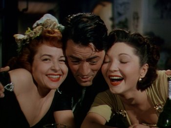 Movie still from “The Snows of Kilimanjaro” (1952), directed by Henry King – A man and two women posing for a picture together; Close Up shot, High angle